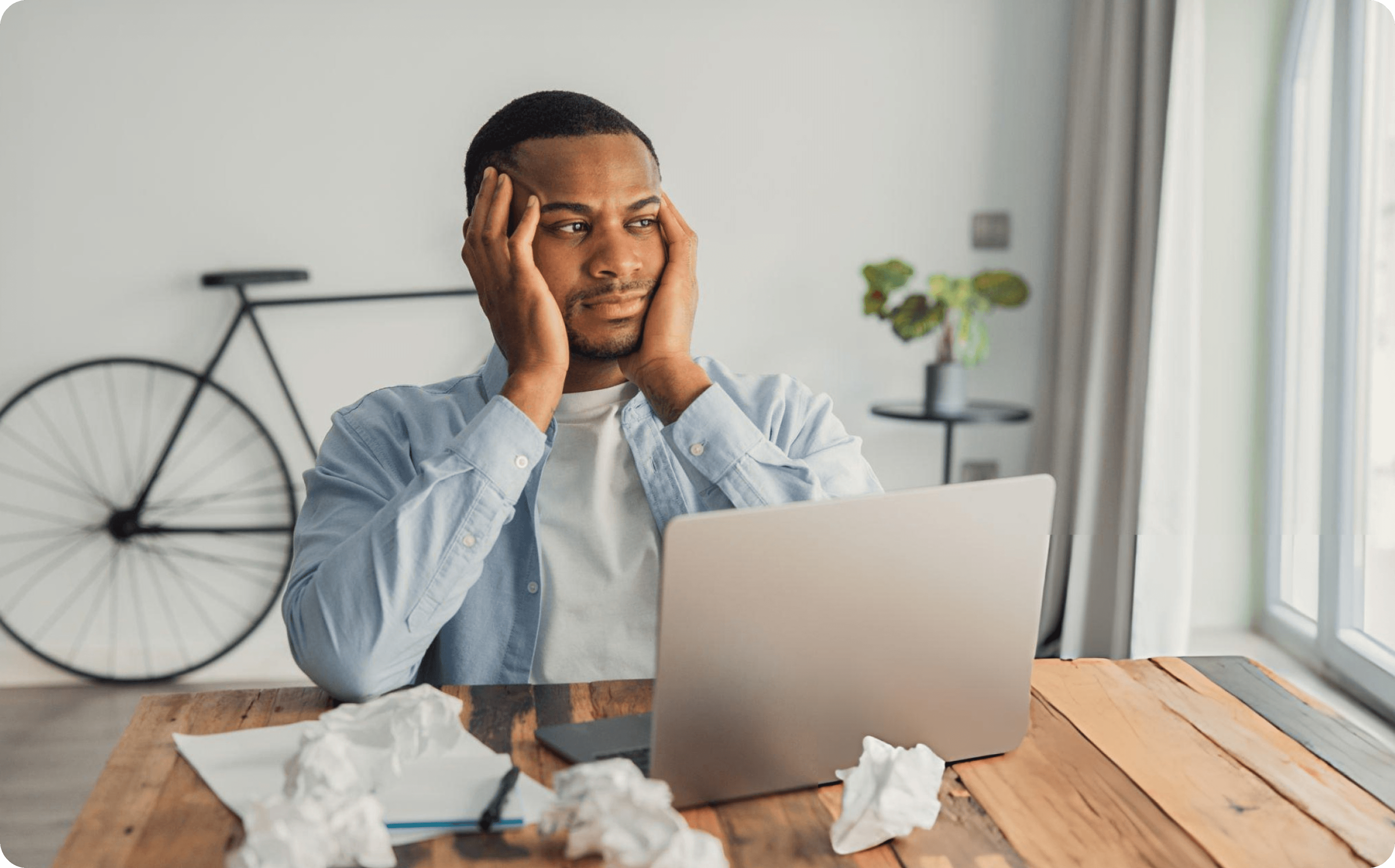 A creator sitting at a desk with crumpled paper, stuck on what to sell